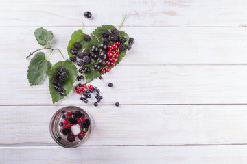 Mulberry berries, blackberries and currants on a white wooden table. The flat composition