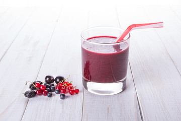 Delicious black currant smoothie with fresh berries on white wood background with copy space. Top view or flat lay