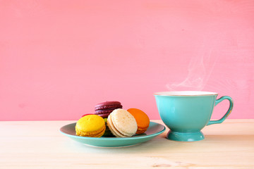 Cup of coffee and colorful macaron on wooden table