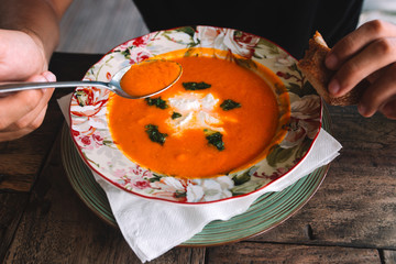 Plate of orange soup with cheese and green leaves on the table	
