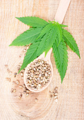 Fototapeta na wymiar Cannabis leaf and seeds on wooden table. Close Up.