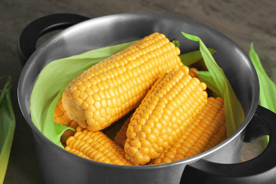 Tasty boiled corncobs in saucepan, close up view
