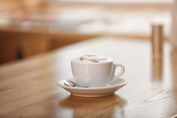 Cup of tasty cappuccino on table in cafe
