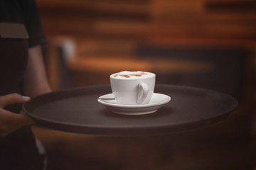 Cup of tasty cappuccino on waiter tray