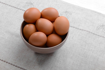 Raw eggs in bowl on tablecloth