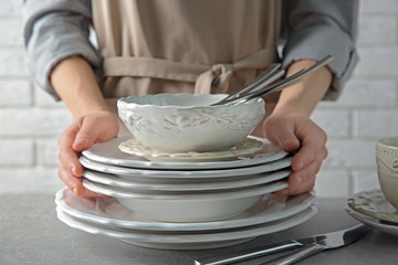 Female hands holding pile of porcelain dishware, closeup