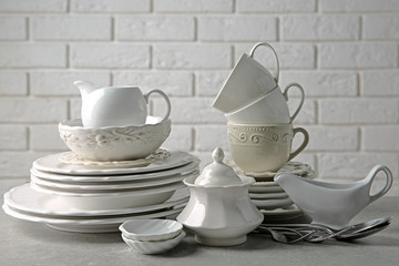 Porcelain dishware on table and white brick wall background