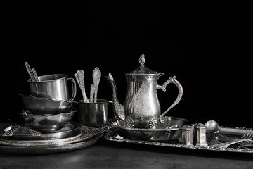 Silver dishware on table and black background