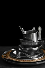 Silver dishware on table and black background