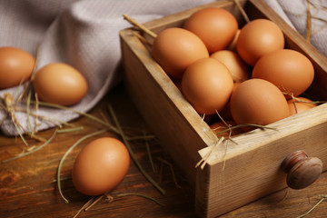 Raw eggs in drawer on wooden background