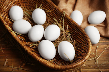 Raw eggs in basket on wooden background © Africa Studio