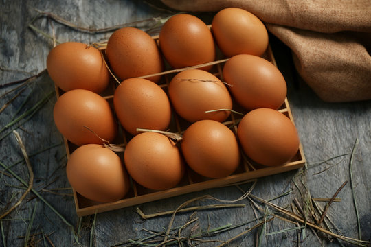 Raw eggs in box on wooden background
