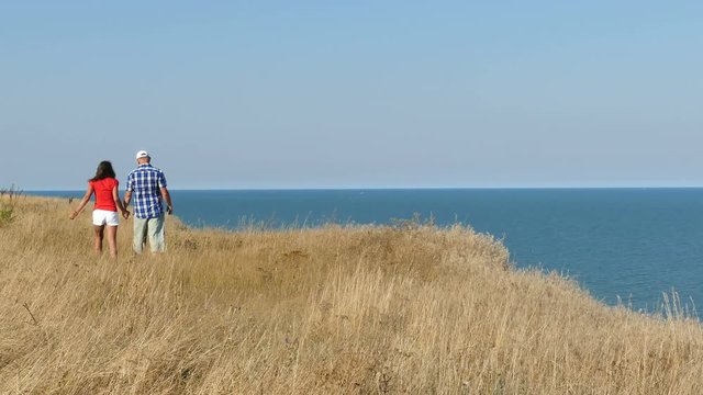 4K. Adult attractive couple walk against  sea in summer day
   
