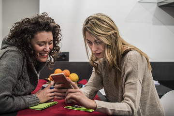 due amiche si divertono e usano uno smartphone