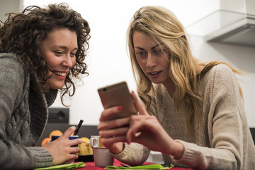 due amiche si divertono e usano uno smartphone