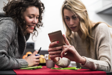 due amiche si divertono e usano uno smartphone