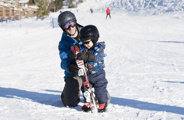 Fototapeta na wymiar Toddler Learning to Ski at a Colorado Resort Dressed Safely with Helmet, Sunglasses & Harness