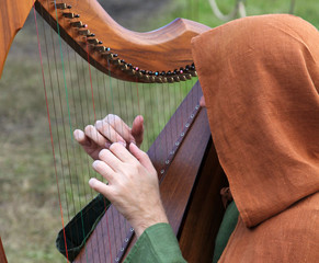 Man in an old dress playing the celtic harp