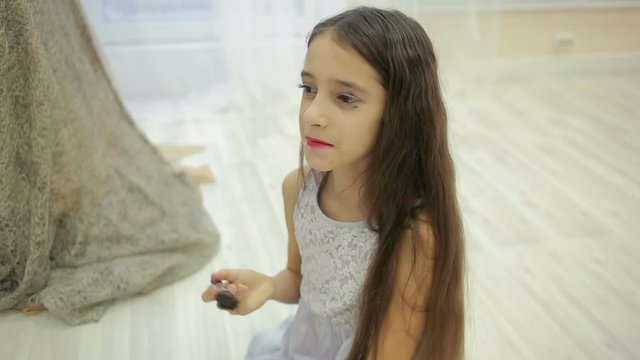 little girl is painted before a mirror her mother's makeup