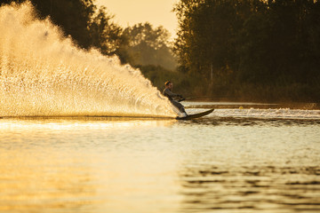 Man riding wakeboard on lake with splashes