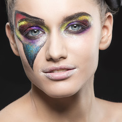 close-up face of young girl with fantasy make-up, blue eyes and perfect skin over black background