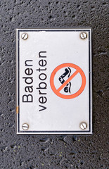 Metallschild "Baden verboten" auf Sichtbeton geschraubt