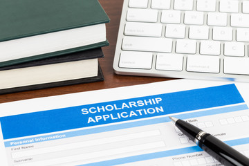 Scholarship application form with pen, keyboard, and text book