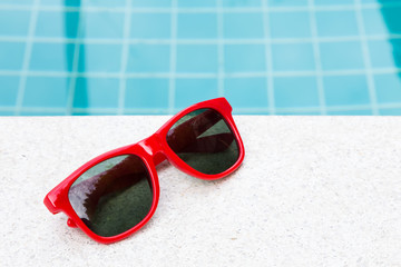 Red sun glasses near swimming pool outdoor