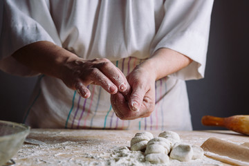 Front view of woman's hands making dough for meat dumplings.