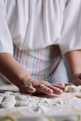 Obraz na płótnie Canvas Front view of woman's hands making dough for meat dumplings.