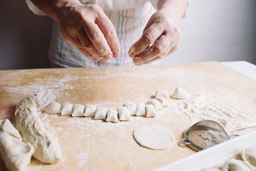 Front view of woman's hands making dough for meat dumplings.