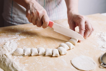 Front view of woman's hands making dough for meat dumplings.