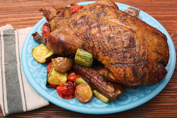 Festive roast duck with vegetables on plate on wooden table