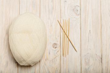 Fototapeta na wymiar White yarn and wooden knitting needles on a light wooden backgro