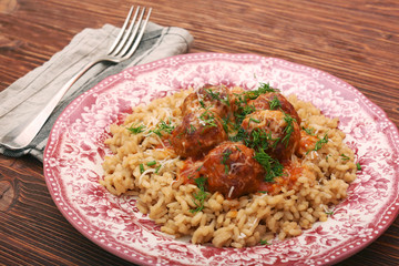 Meatballs in tomato sauce with rice in a bowl, wooden background