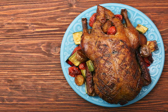 Festive roast duck with vegetables on plate on wooden table