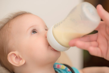 Mother feeds baby from a bottle of milk