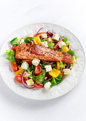 Fried Salmon steak with fresh vegetables salad, feta cheese. concept healthy food.