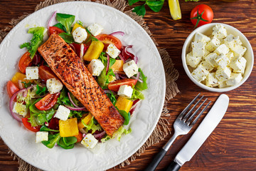 Fried Salmon steak with fresh vegetables salad, feta cheese. concept healthy food.