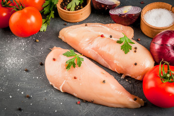 Raw uncooked chicken fillet on a cutting table with ingredients for cooking, copy space