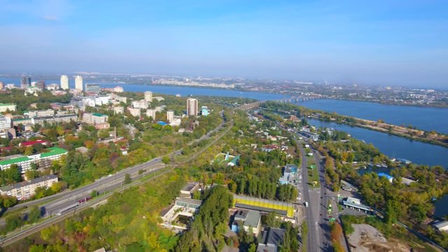 Aerial shot. The camera raise above the road with traffic, over modern buildings and river Dnepr in Dnepr city, Ukraine. 4K, Ultra HD video.