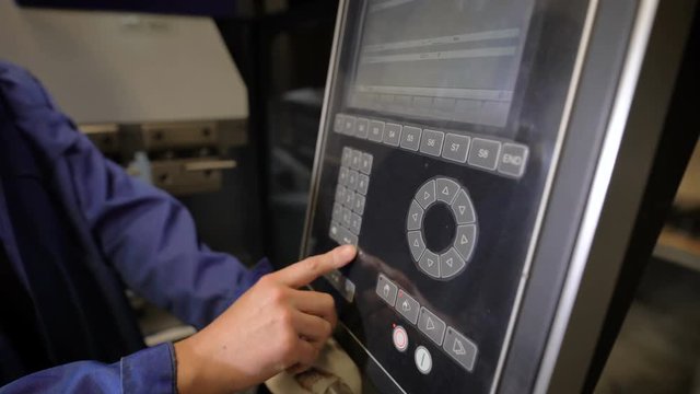 The worker presses buttons of the panel of the machine tool with numerical programmed control. The engineer configures a program for operation of the machine.
