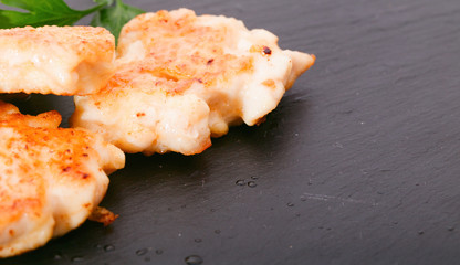 Pieces of chicken meat with edible greens on a board from slate