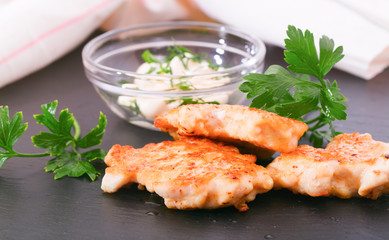 Pieces of chicken meat with edible greens on a board from slate