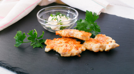 Pieces of chicken meat with edible greens on a board from slate