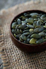 pumpkin seeds in a bowl over wooden surface