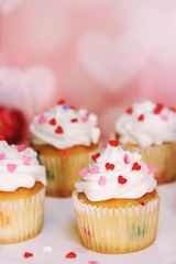 Homemade Valentine cupcakes topped with heart shaped sprinkles on Pink background,selective focus