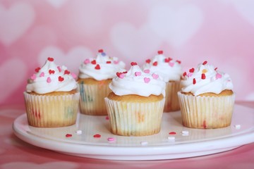 Homemade Valentine cupcakes topped with heart shaped sprinkles on Pink background,selective focus