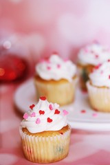 Homemade Valentine cupcakes topped with heart shaped sprinkles on Pink background,selective focus