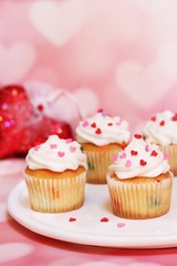 Homemade Valentine cupcakes topped with heart shaped sprinkles on Pink background,selective focus